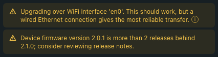 Pre-flight dialog warnings close-up: two amber warning rows side by side. The first reads 'Device is on a Wi-Fi interface — wired Ethernet is strongly recommended for firmware upgrades.' The second reads 'Device firmware version 2.0.1 is more than 2 releases behind 2.1.0; consider reviewing release notes.'